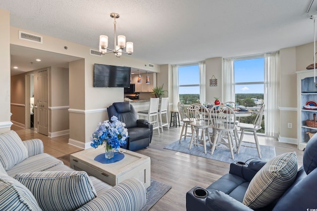 living area featuring a wall of windows, an inviting chandelier, light wood-style floors, and visible vents