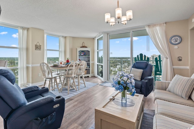 living area featuring a wealth of natural light, floor to ceiling windows, an inviting chandelier, and wood finished floors