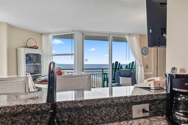 kitchen featuring a textured ceiling, a water view, and expansive windows