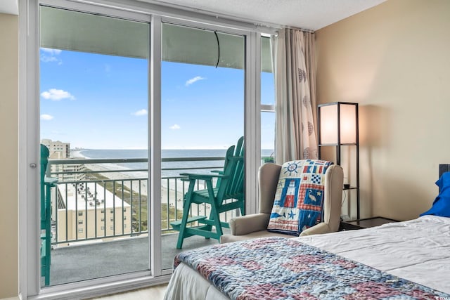 bedroom featuring a wall of windows, multiple windows, a textured ceiling, and a water view