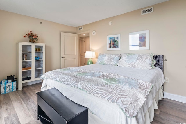 bedroom with wood finished floors, visible vents, and baseboards