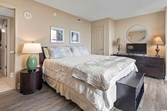 bedroom with visible vents, baseboards, and wood finished floors