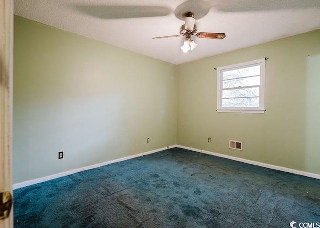 empty room with dark carpet, a ceiling fan, baseboards, and visible vents
