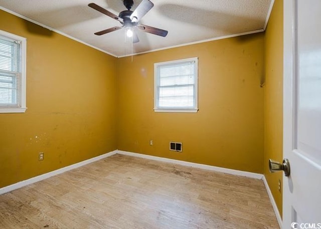 spare room with visible vents, light wood-style flooring, crown molding, and ceiling fan