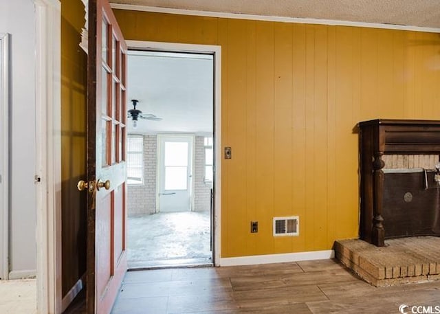 doorway to outside featuring visible vents, wood finished floors, and wooden walls