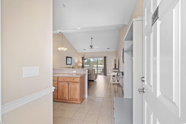 kitchen with light tile patterned flooring, lofted ceiling, ceiling fan with notable chandelier, and decorative light fixtures