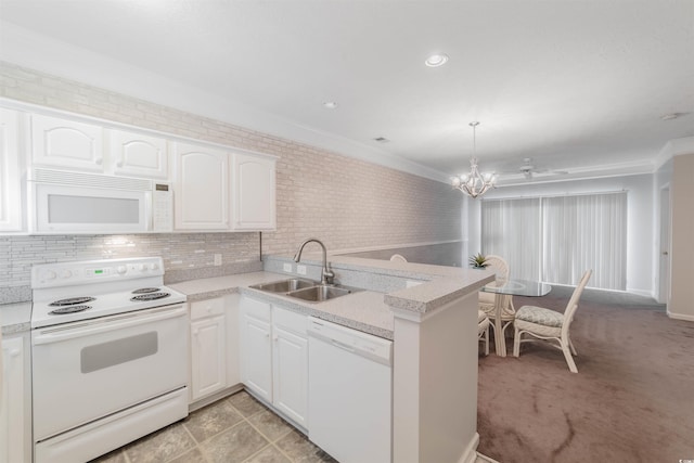 kitchen featuring white appliances, a peninsula, ornamental molding, a sink, and light countertops