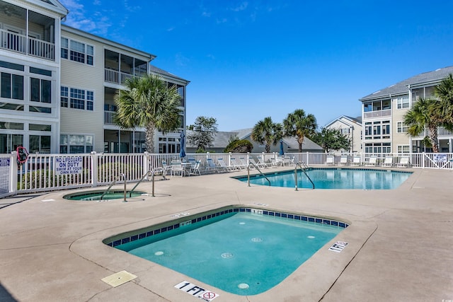 community pool featuring a patio, fence, and a hot tub