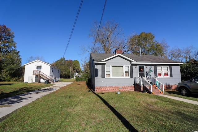 bungalow-style home with crawl space, a chimney, a front yard, and a shingled roof