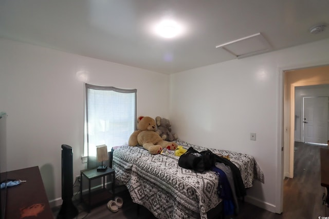 bedroom featuring attic access, wood finished floors, and baseboards