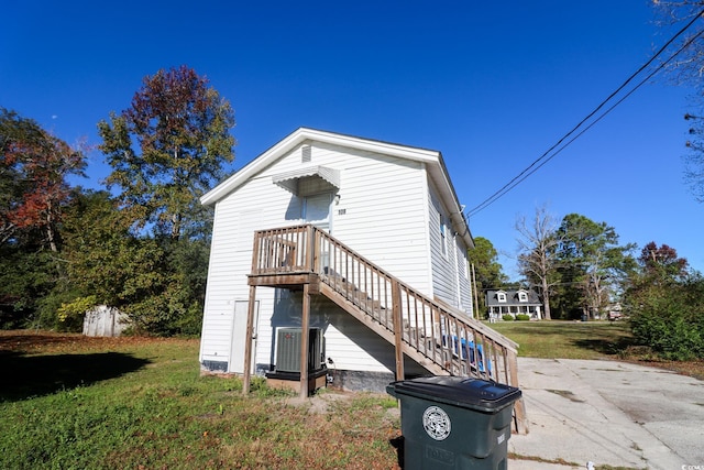 back of property featuring central air condition unit, stairway, and a yard