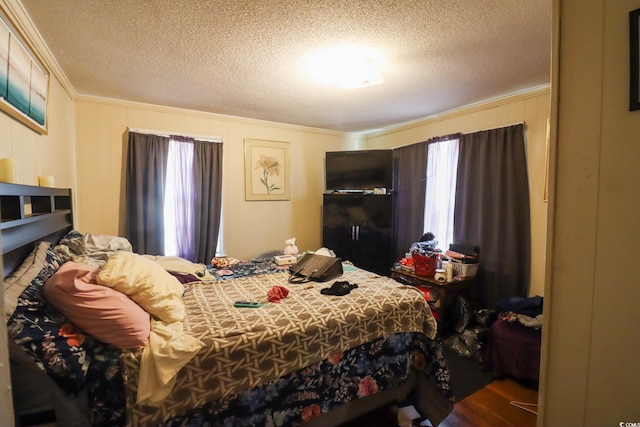 bedroom with wood finished floors, a textured ceiling, and ornamental molding