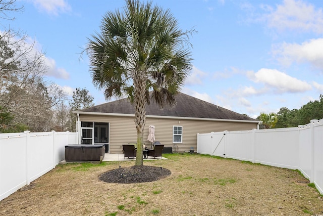 rear view of property with a patio area, a fenced backyard, a lawn, and a hot tub