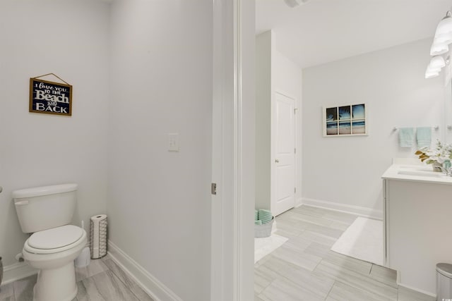 bathroom featuring toilet, vanity, and baseboards