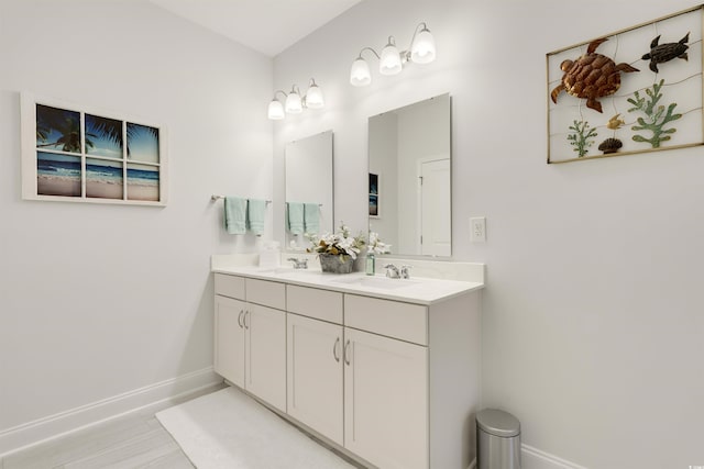 bathroom with double vanity, a sink, and baseboards