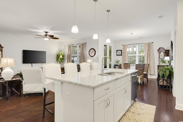 kitchen featuring pendant lighting, white cabinetry, a sink, an island with sink, and a kitchen breakfast bar