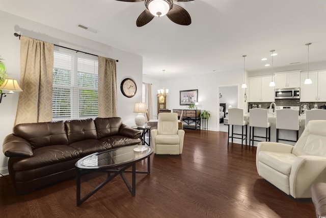 living room featuring baseboards, visible vents, dark wood-type flooring, ceiling fan with notable chandelier, and recessed lighting