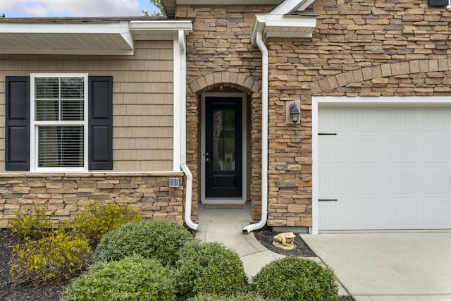 entrance to property featuring an attached garage and stone siding