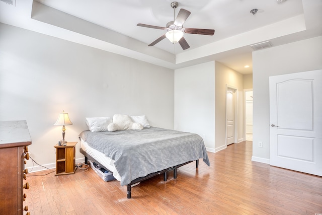 bedroom with a tray ceiling, ceiling fan, and hardwood / wood-style flooring