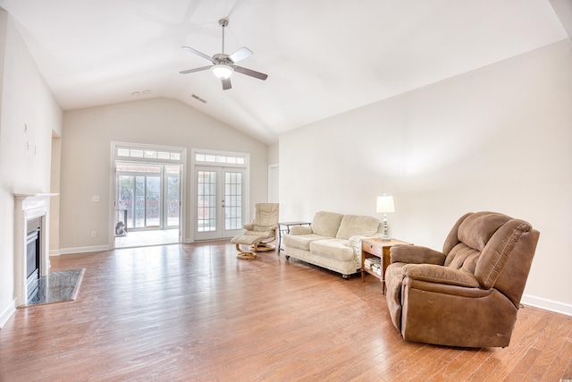 living room with ceiling fan, light hardwood / wood-style flooring, a fireplace, and french doors