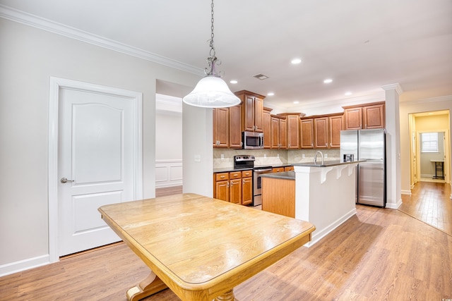 kitchen with light hardwood / wood-style flooring, a breakfast bar, appliances with stainless steel finishes, hanging light fixtures, and ornamental molding