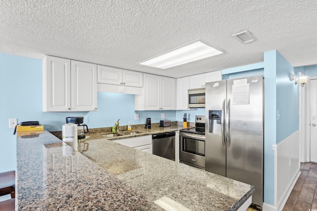 kitchen featuring kitchen peninsula, sink, stainless steel appliances, and white cabinets