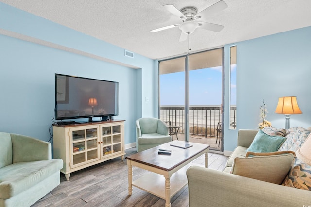 living room featuring hardwood / wood-style floors, a textured ceiling, ceiling fan, and floor to ceiling windows