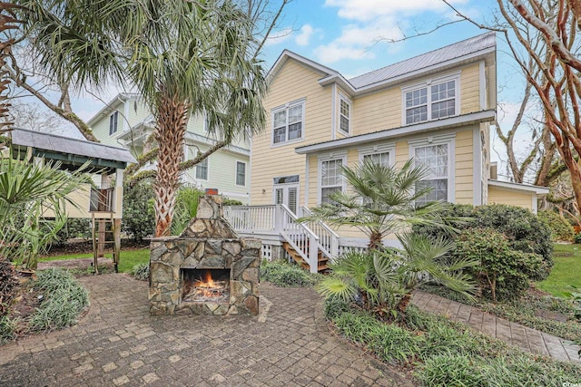 view of front of property featuring a patio and an outdoor stone fireplace