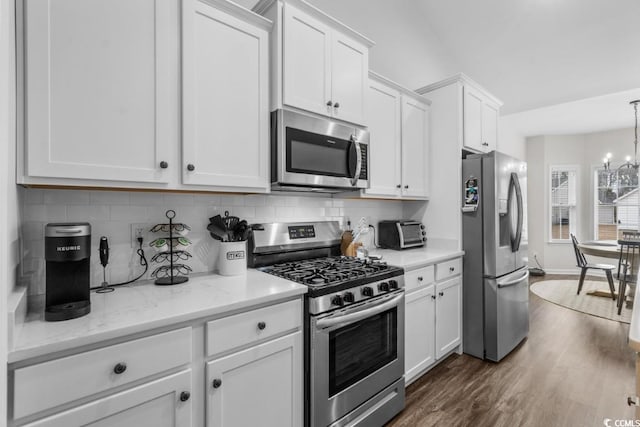 kitchen featuring stainless steel appliances, dark wood-style flooring, white cabinetry, and light stone countertops