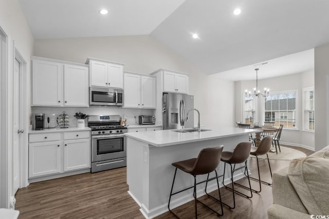 kitchen featuring appliances with stainless steel finishes, a breakfast bar, a kitchen island with sink, light countertops, and white cabinetry