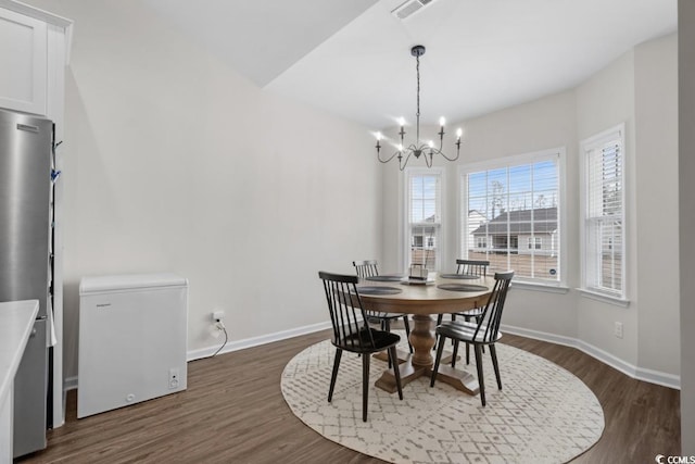 dining room featuring dark wood-type flooring, an inviting chandelier, visible vents, and baseboards