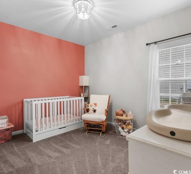 carpeted bedroom featuring visible vents and a crib