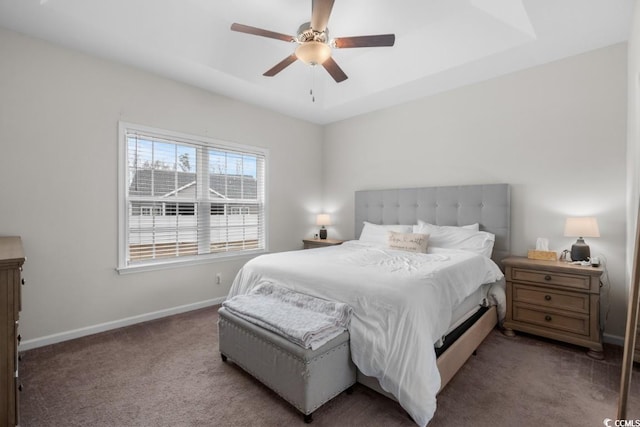 bedroom featuring a ceiling fan, carpet, a tray ceiling, and baseboards