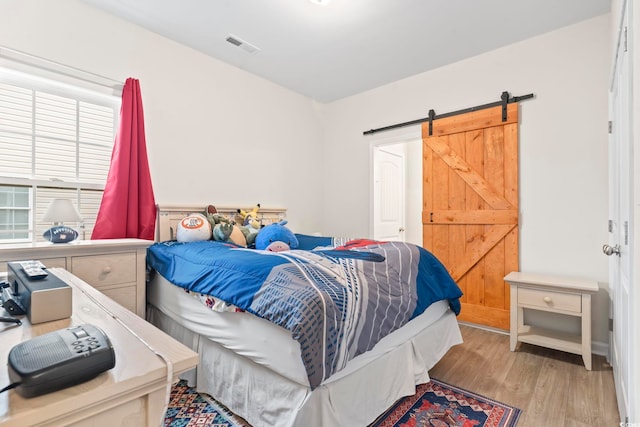 bedroom featuring a barn door and light wood-type flooring