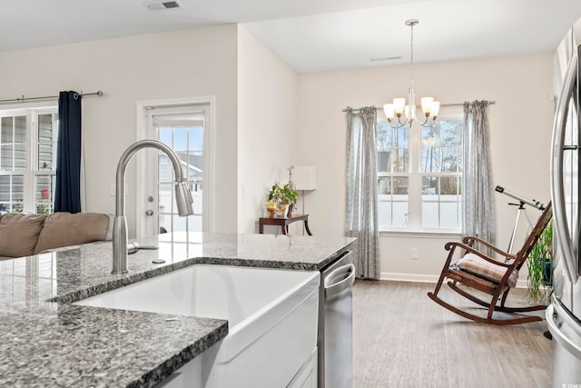 kitchen with sink, hanging light fixtures, hardwood / wood-style floors, white cabinets, and dark stone counters