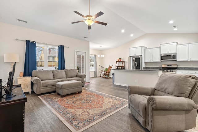 living room with ceiling fan with notable chandelier, dark wood-type flooring, and vaulted ceiling