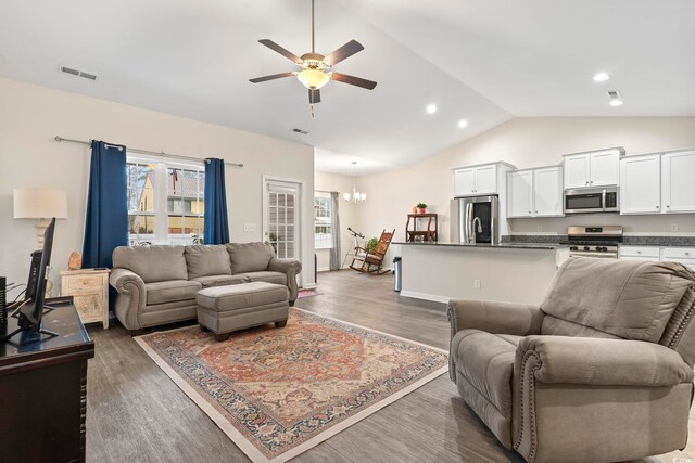 living room with ceiling fan with notable chandelier, dark wood-type flooring, and vaulted ceiling