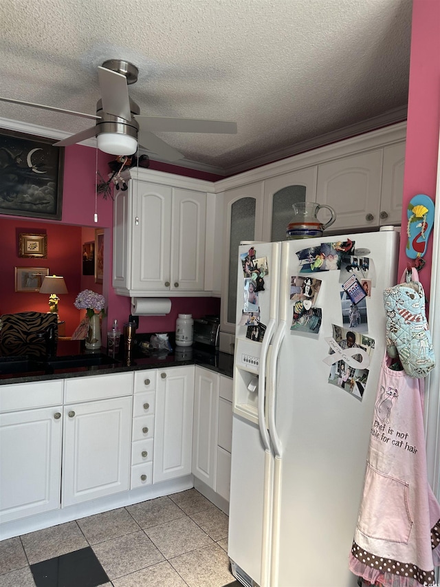 kitchen with white cabinetry, sink, white refrigerator with ice dispenser, ceiling fan, and a textured ceiling