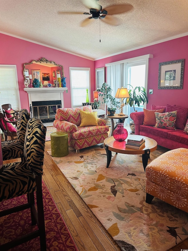 living room featuring crown molding, ceiling fan, wood-type flooring, and a textured ceiling