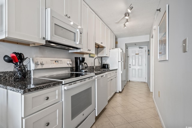 kitchen with sink, white appliances, a textured ceiling, white cabinets, and light tile patterned flooring