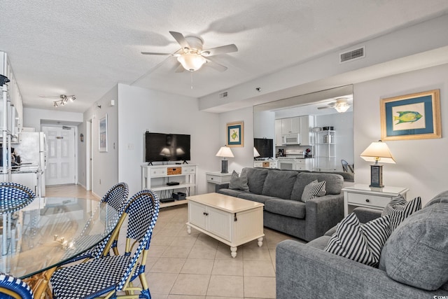 tiled living room with ceiling fan and a textured ceiling