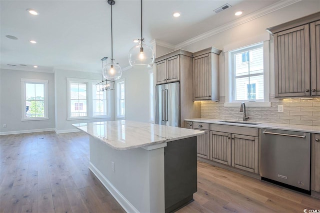 kitchen with sink, hanging light fixtures, a center island, stainless steel appliances, and crown molding