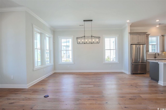 unfurnished dining area with wood-type flooring, a chandelier, and crown molding