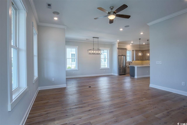 unfurnished living room with ceiling fan with notable chandelier, ornamental molding, and dark hardwood / wood-style floors