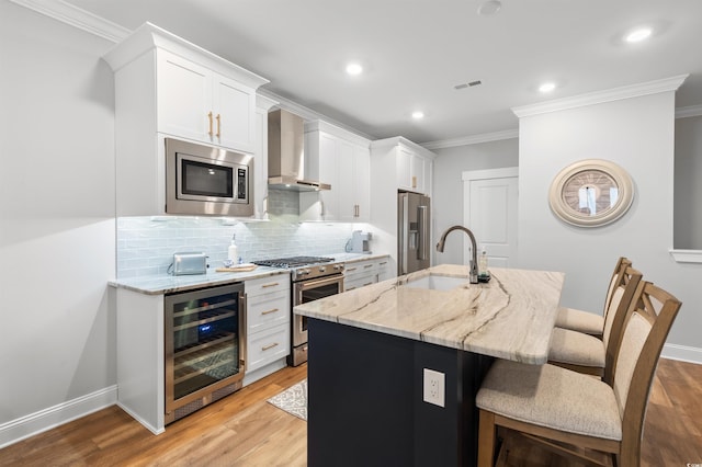 kitchen with premium appliances, an island with sink, beverage cooler, and white cabinets