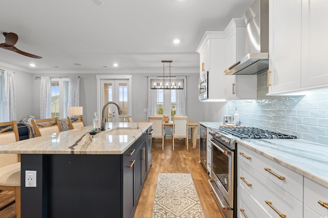 kitchen with wall chimney exhaust hood, stainless steel appliances, an island with sink, and a breakfast bar area