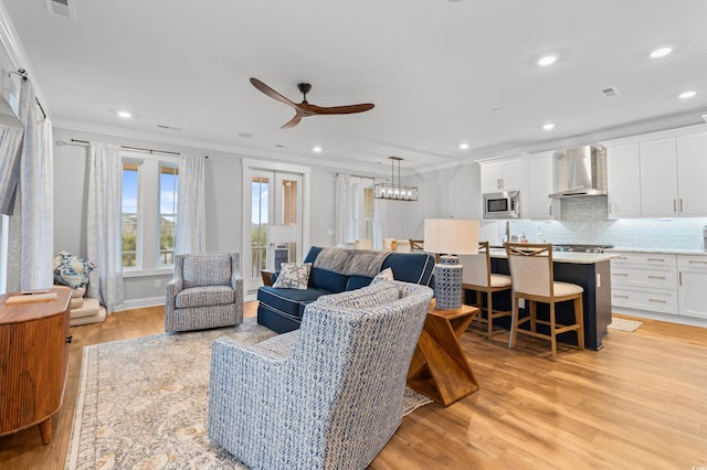 living room featuring ornamental molding, ceiling fan, and light hardwood / wood-style flooring