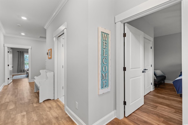 hallway featuring crown molding and light hardwood / wood-style flooring