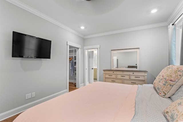 bedroom with ornamental molding, a walk in closet, and hardwood / wood-style floors