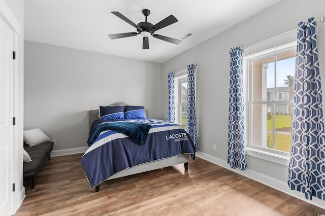 bedroom with multiple windows, wood-type flooring, and ceiling fan